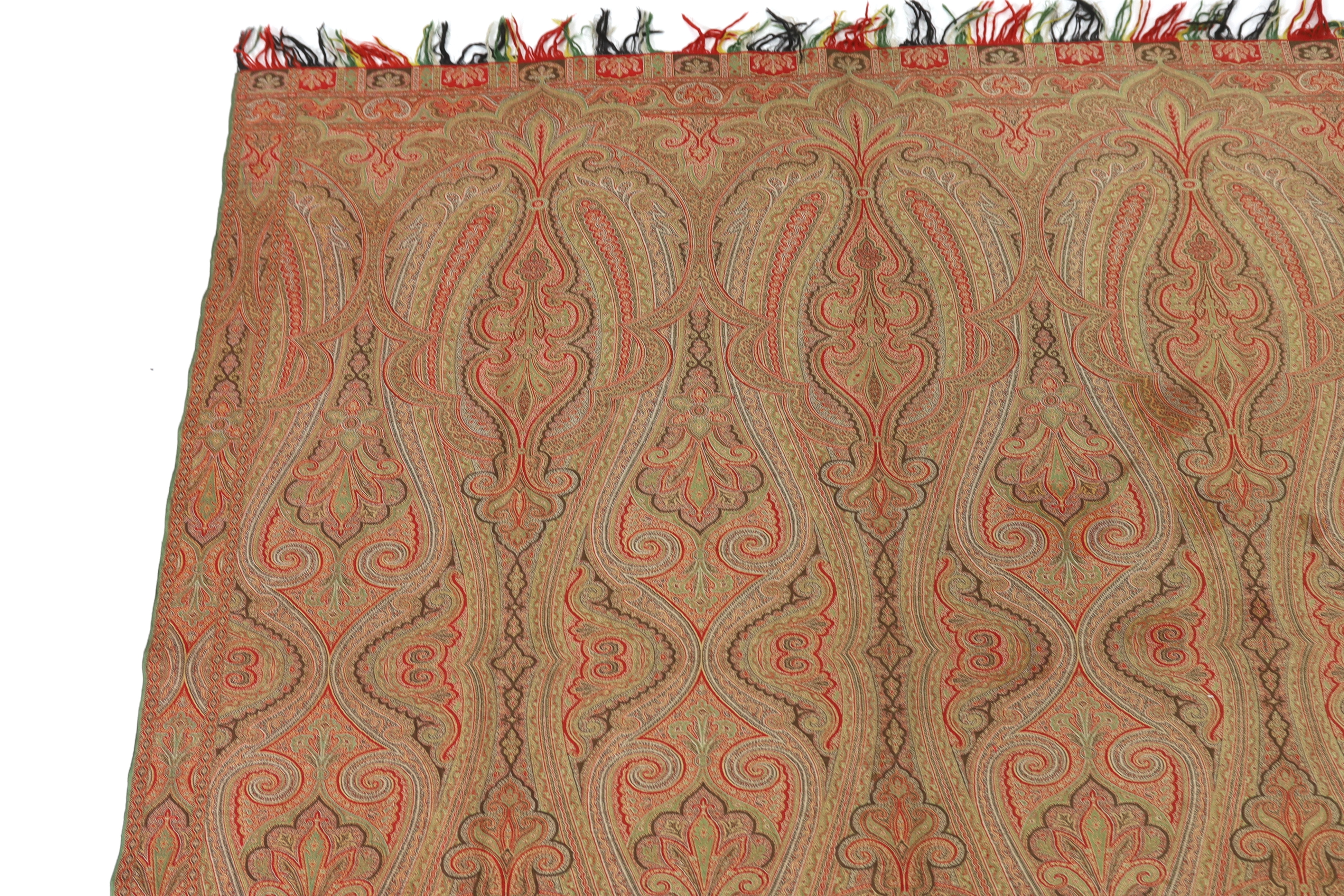 An 1860’s, reversible woven wool Paisley shawl, woven with green, red, ochre and brown, with a woven border and fringing both ends. 166cm wide x 169cm long